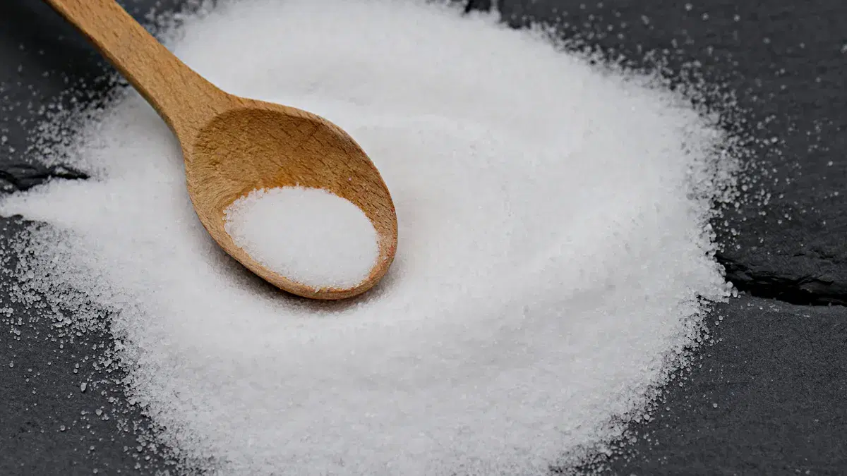 Close-up of a wooden spoon with sea salt on a slate background, perfect for culinary themes.